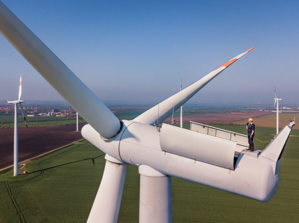 Man standing on top of a wind turbine.