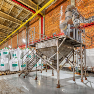 Large industrial warehouse of chemicals. Large white bags filled with powder are arranged in long rows.