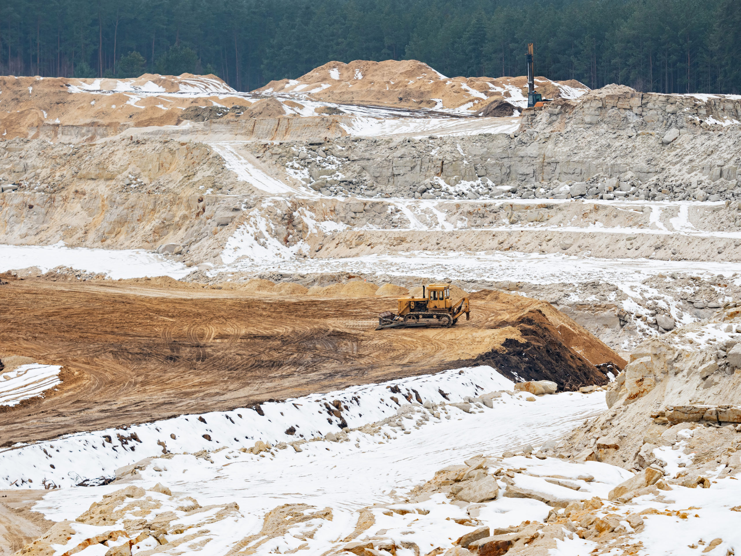 Excavators on a quarrying site working on silica glass sand. General open mine pit scene.