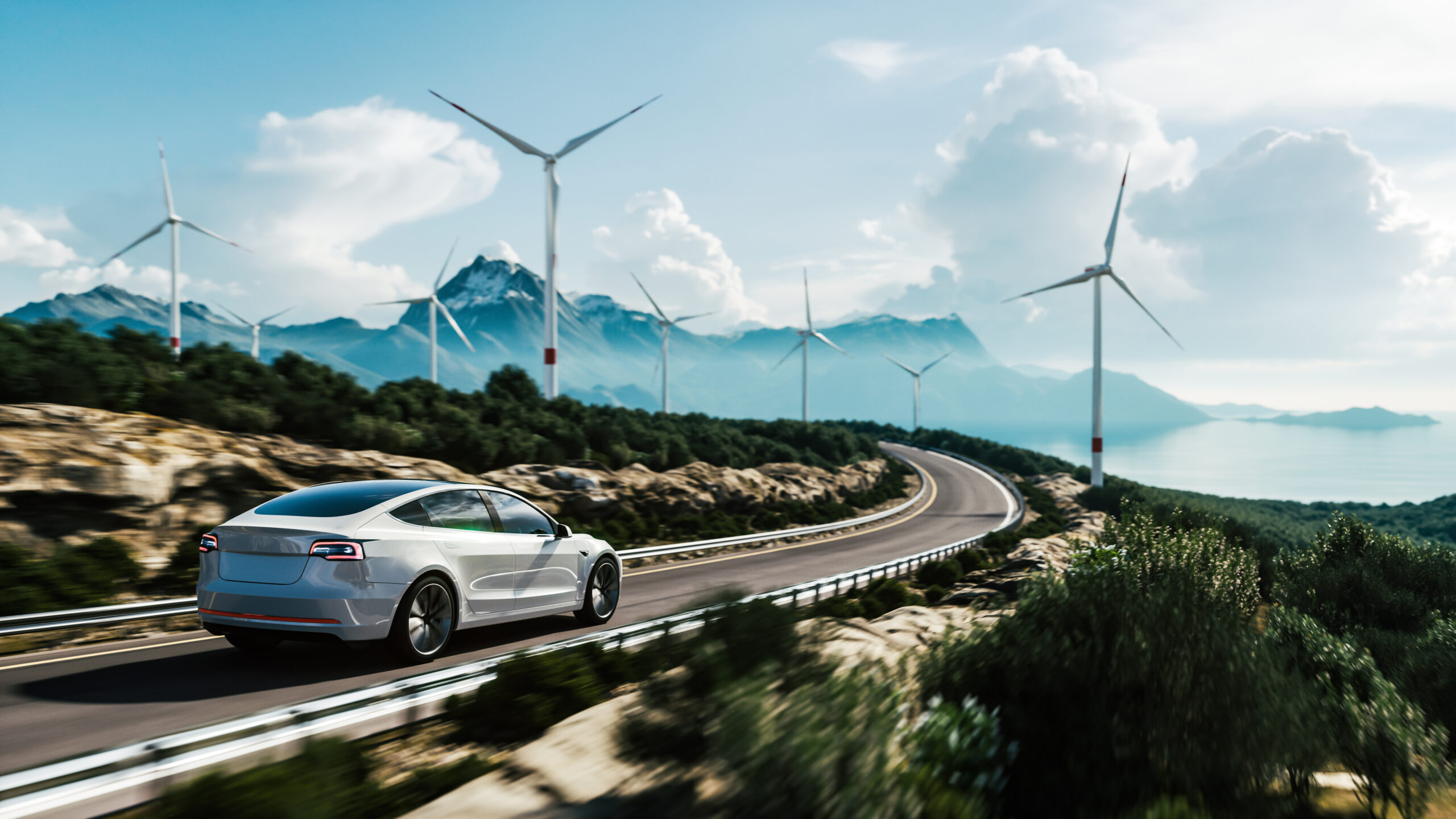 Electric vehicle on mountain road driving past wind turbines