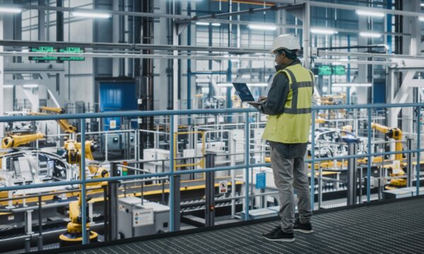 Individual in a high visibility vest overlooking an automated factory floor