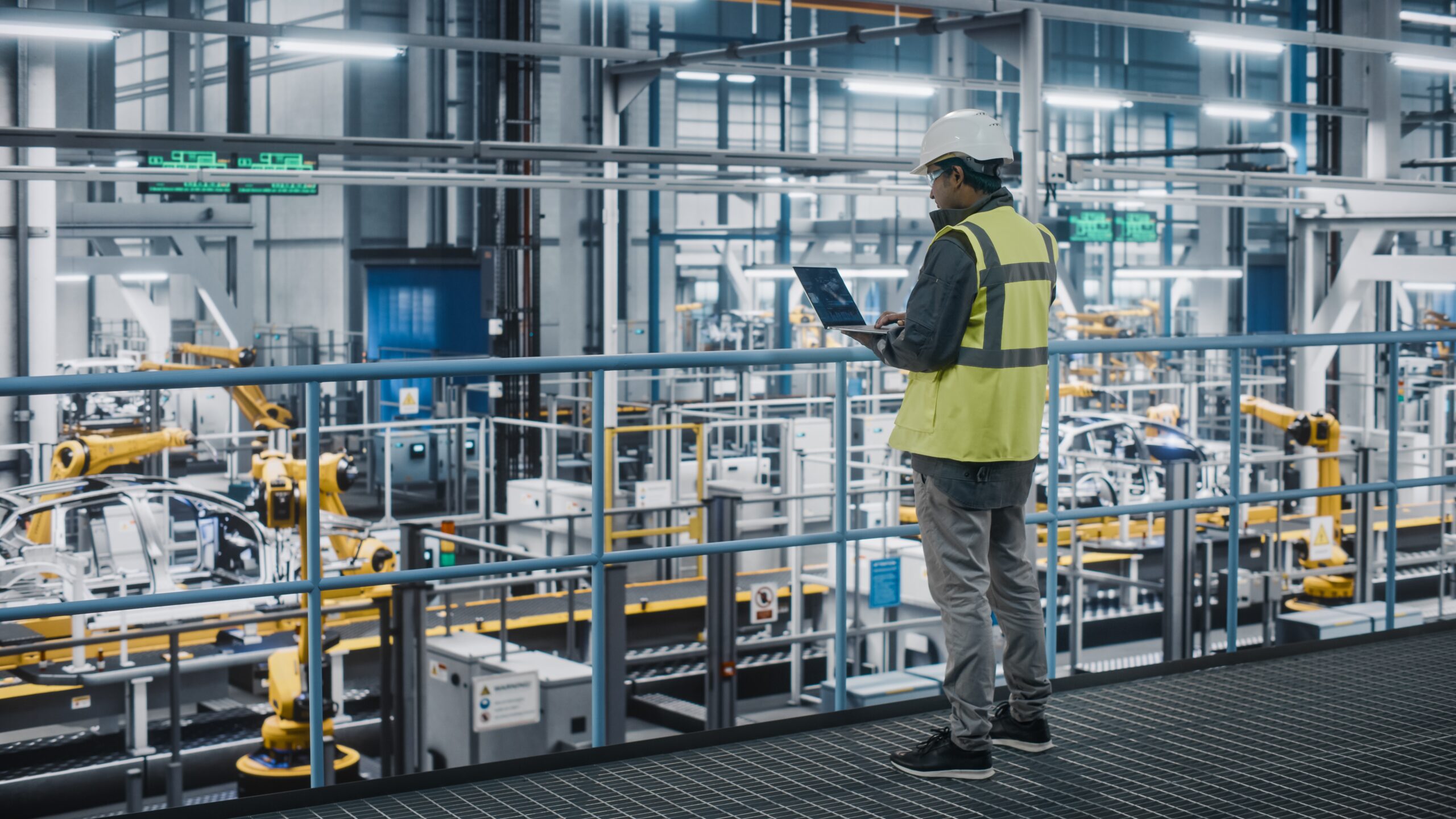 Individual in a high visibility vest overlooking an automated factory floor